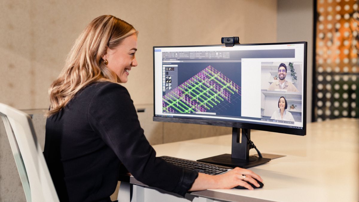 A female engineer collaborates remotely with international colleagues via an online video conference. Her computer screen displays a technical CAD drawing, highlighting the teamwork and innovation of the new generation of tech talent.