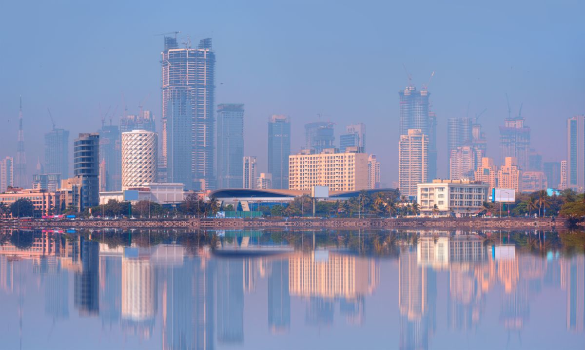 Een stedelijk panorama met hoge gebouwen en een reflectie in het water, symbool voor technologische vooruitgang en de groei van de tech-industrie.